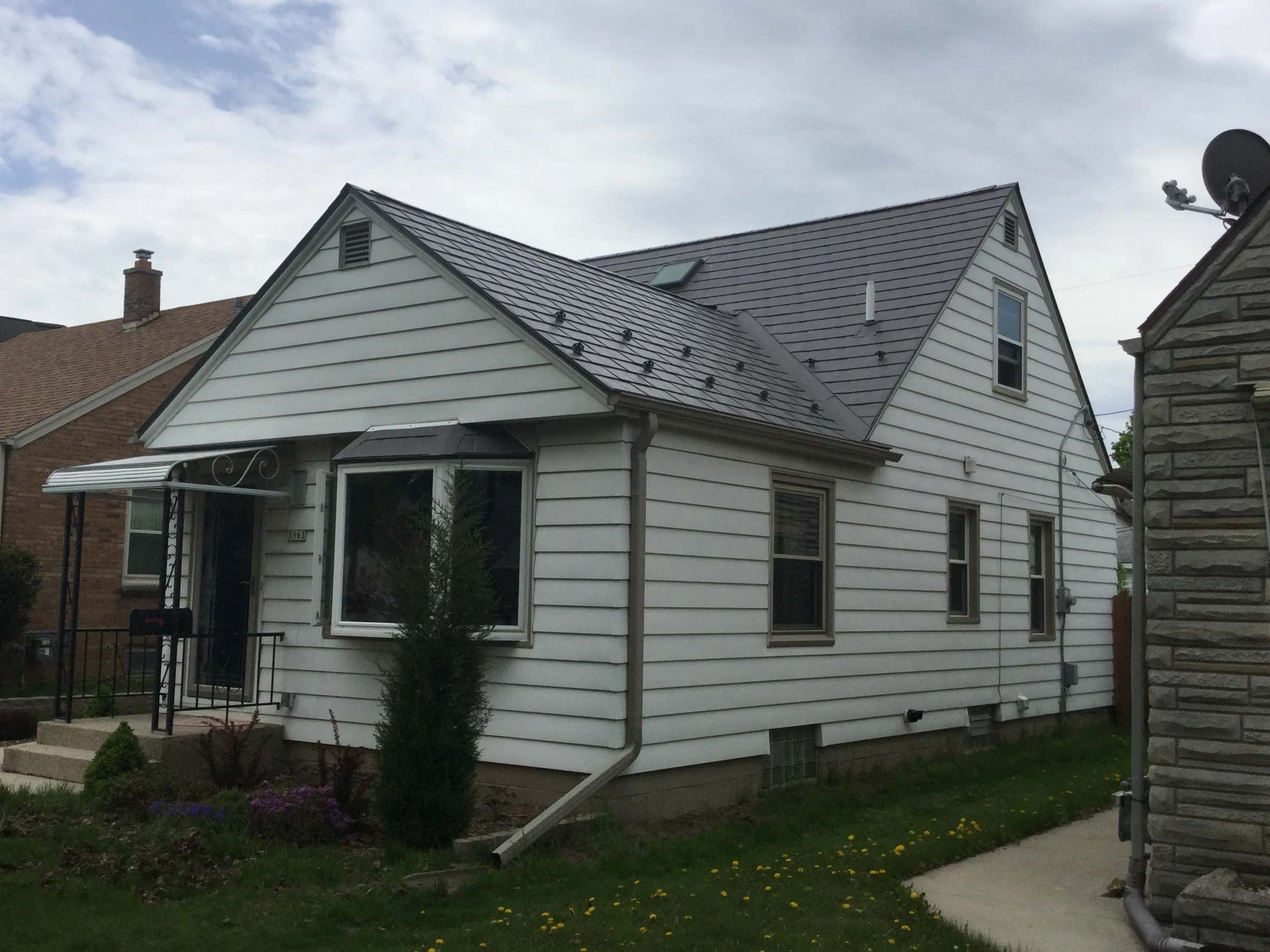 Weathered Interlock Slate aluminum roof on a white single-family home with dormers in an urban, Milwaukee, Wisconsin
