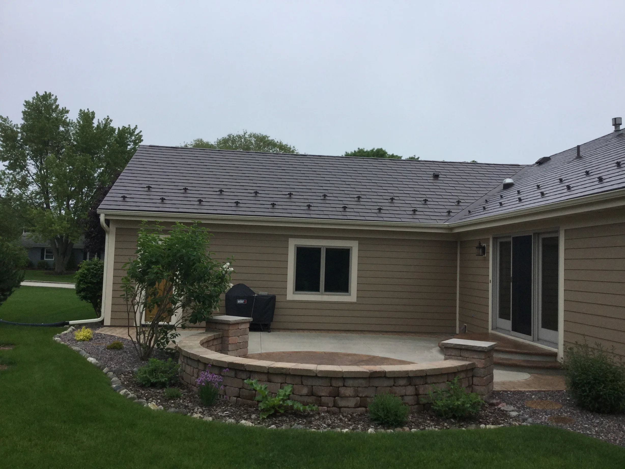 Colonial Brown Interlock Slate aluminum roof on a brown single-storey home with a metal roof among tall, Port Washington, Wisconsin