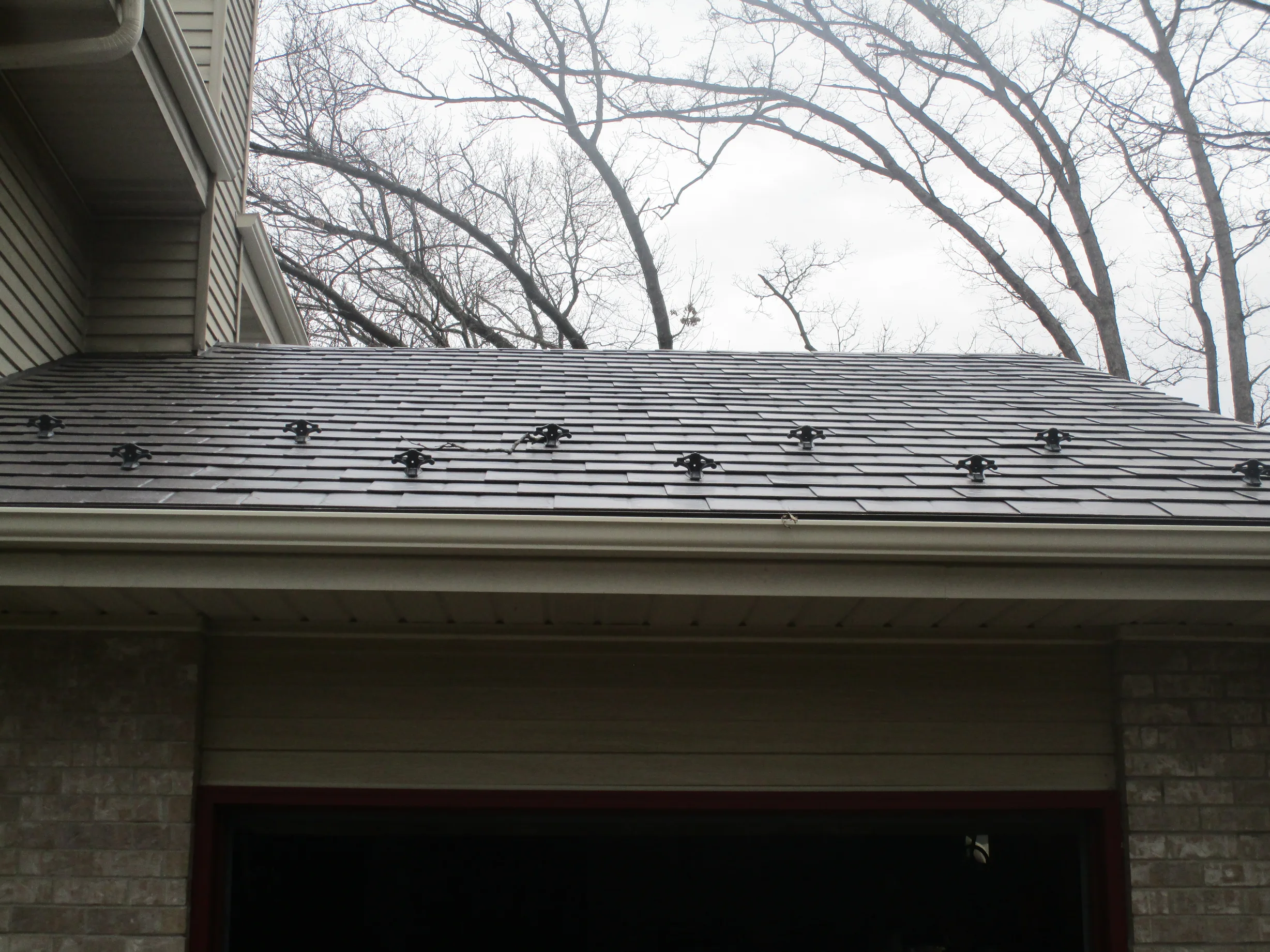 Tudor Brown Interlock Slate aluminum roof on a two-storey Tudor home in a wooded setting, Delafield, Wisconsin