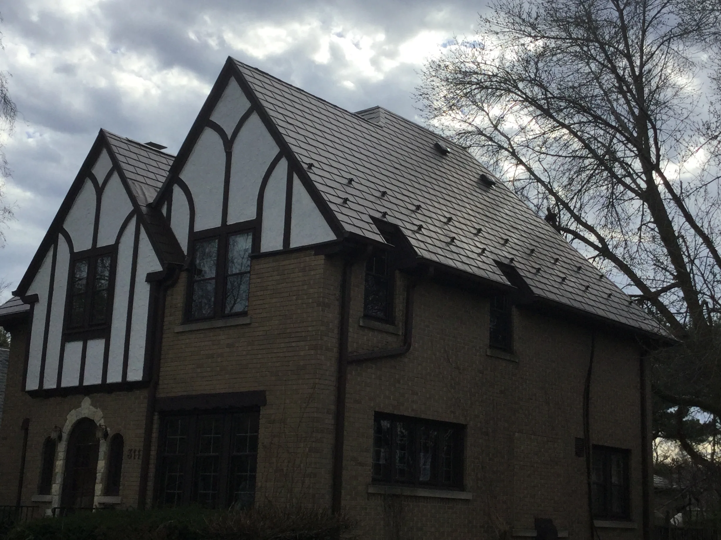 Colonial Brown Interlock Slate aluminum roof on a brown colonial home with dormers in a forested setting, Milwaukee, Wisconsin