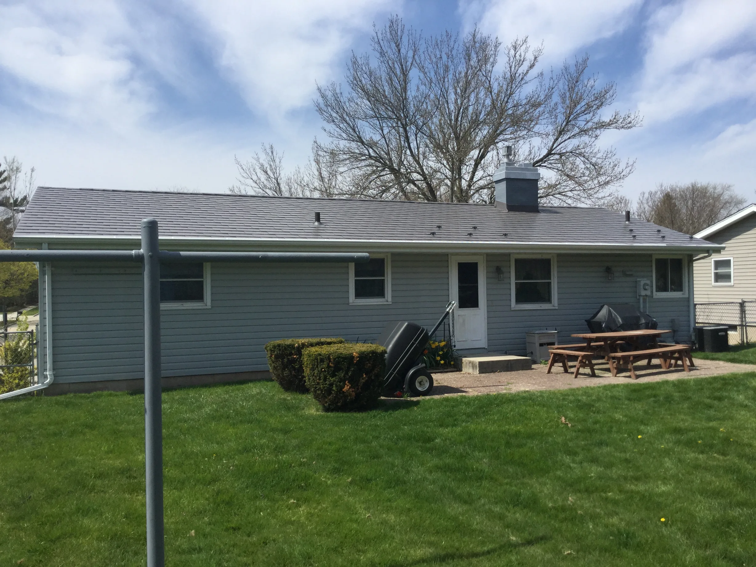 Weathered Interlock Slate aluminum roof on a grey ranch-style home with a metal roof in a lush green, Sheboygan, Wisconsin