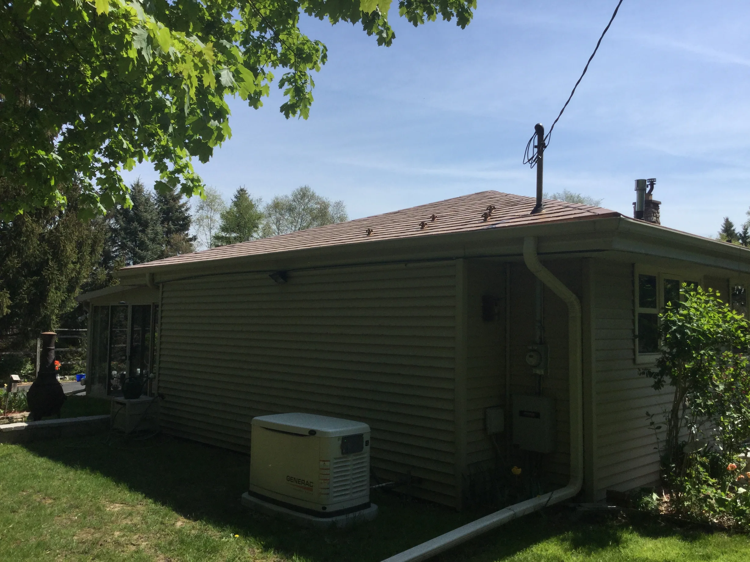Aged Copper Interlock Slate aluminum roof on a ranch-style home with a metal roof among tall trees in a, Colgate, Wisconsin