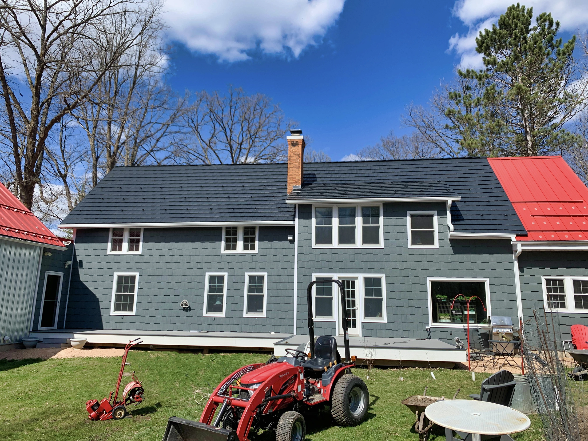 Rear elevation of a 2-story colonial home with black Interlock aluminum shake metal roofing, brick chimney, and grey shake siding in Birchwood, WI.